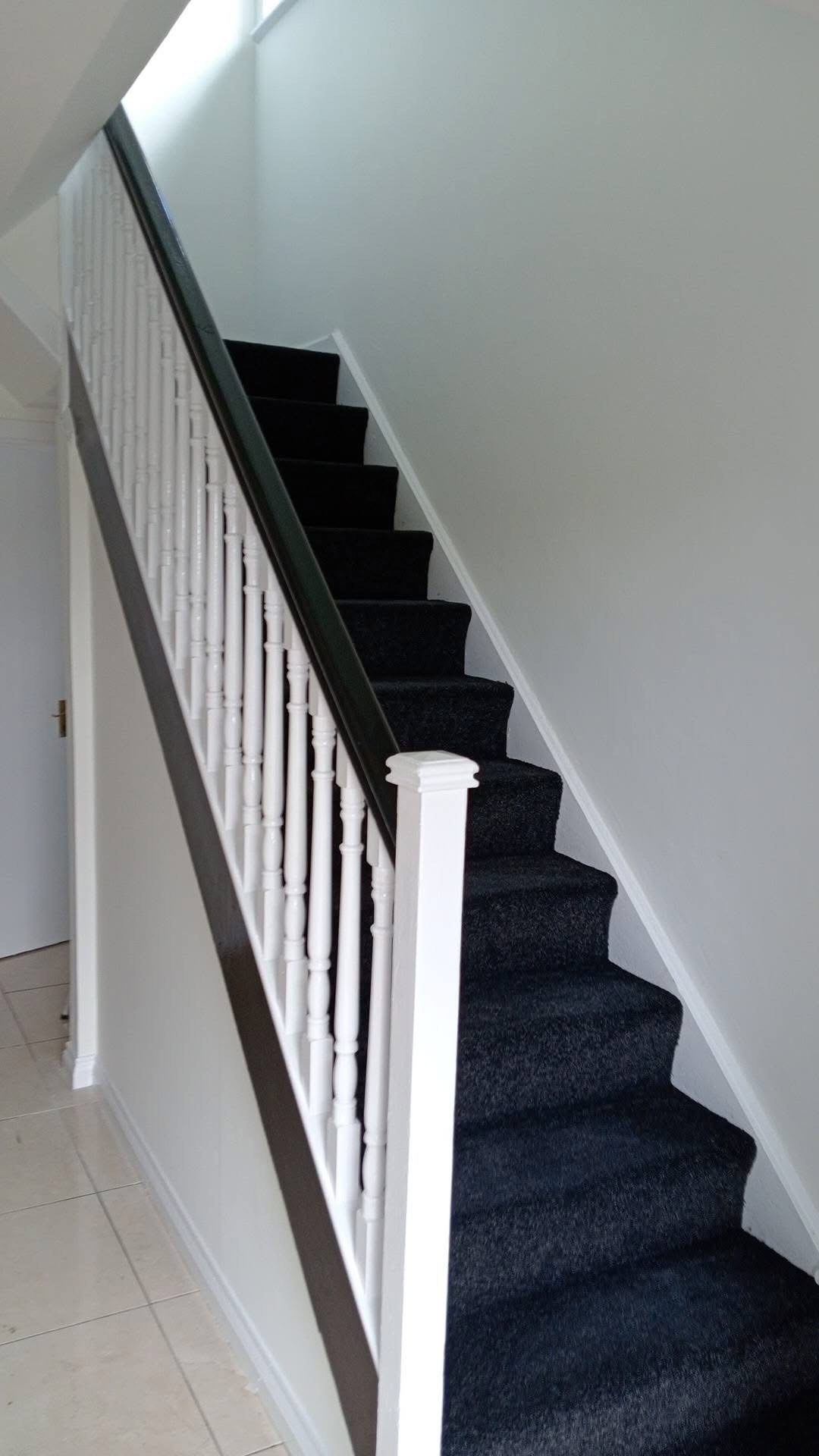 Hallway staircase after painting — fresh white walls and new carpet